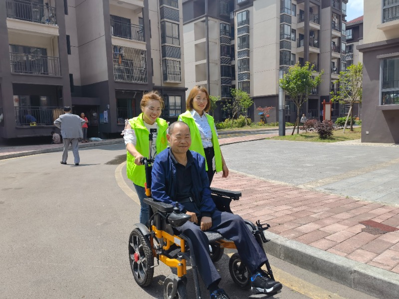 乌当区残疾人就业创业扶贫促进会日间托养服务工作人员帮助谷恒吉在晴朗日外出2.jpg